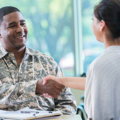 Cheerful mid adult African American army recruitment officer shakes hands with a potential female recruit.
